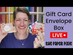 a woman is holding up some cards in front of her face and the words give card envelope box