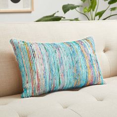 a white couch with a blue and green striped pillow on it's backrest