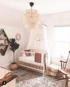 a baby's room with a crib, rocking chair, and hanging lamp