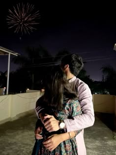 a man and woman kissing in front of a firework display at the end of their night