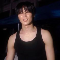 a young man with black hair wearing a tank top