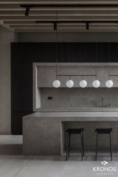 a kitchen with two stools next to an island and three lights hanging from the ceiling