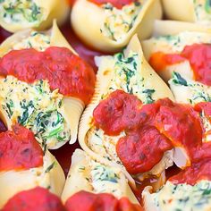 several stuffed shells with sauce and spinach leaves on them are shown in close up