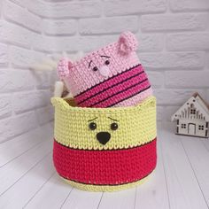 two crocheted animals in a basket on a white table next to a house