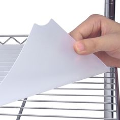 a hand holding a piece of paper over a rack