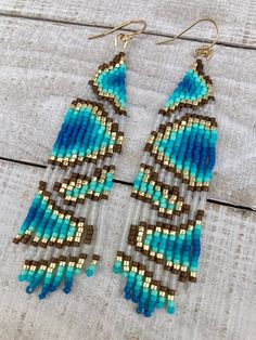 two pairs of beaded earrings on top of a wooden table