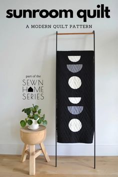 a black and white quilt hanging on a wall next to a potted plant