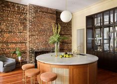 an image of a kitchen with brick walls and marble counter tops in the center, surrounded by stools