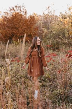 a woman is walking through the tall grass