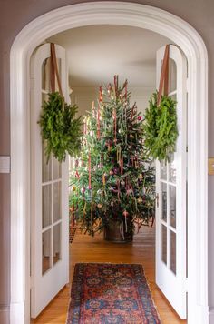 a christmas tree sitting in the middle of a doorway with two wreaths hanging from it's sides