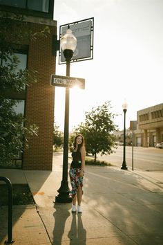 a woman standing under a street sign next to a lamp post