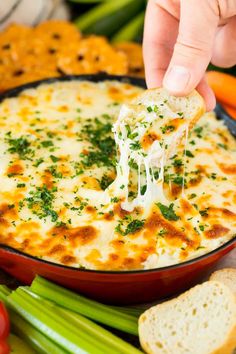 a person dipping cheese into a bowl of dip