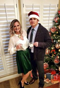 a man and woman standing in front of a christmas tree