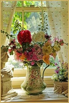 a vase filled with lots of flowers sitting on top of a table next to a window