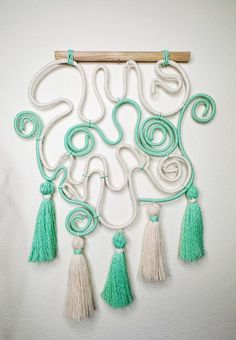 a white wall hanging with green tassels on it