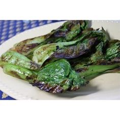 grilled green vegetables on a white plate sitting on a blue and white checkered tablecloth