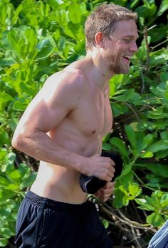 a shirtless man is jogging in the woods with his head turned to the side