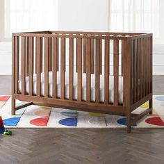 a baby crib sitting on top of a wooden floor next to a white rug