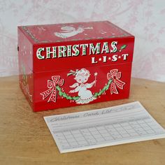 a red christmas card box sitting on top of a table next to a piece of paper