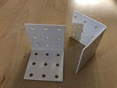 two metal brackets sitting on top of a wooden floor