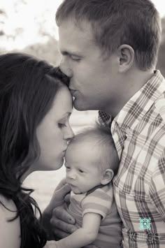 a man and woman are kissing their baby