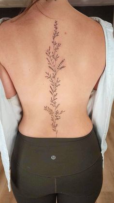 the back of a woman's body with a flower tattoo on her lower back