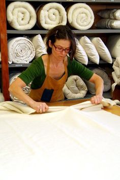 a woman is working on an unmade bed in a room filled with white linens