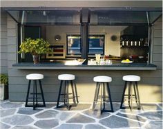 three stools are sitting in front of a bar that is built into the side of a building