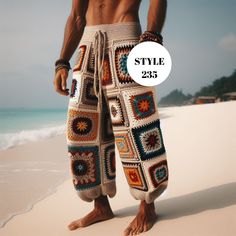 a man standing on top of a sandy beach next to the ocean wearing crocheted pants