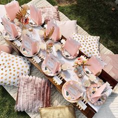 a table set up with pink and gold plates, napkins and place settings on it