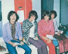 four people sitting next to each other in front of a red and white wall,