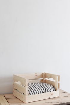 a bed made out of wooden crates sitting on top of a table next to a white wall