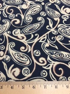 a ruler is next to a black and white paisley print fabric with swirls on it