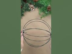 someone is holding a wire ball with pine cones on it