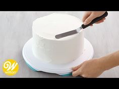 someone is cutting into a white cake with a knife