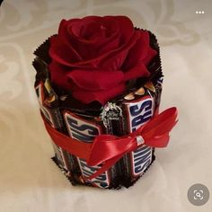 a candy bar wrapped in chocolate with a red rose on top and ribbon around the wrapper