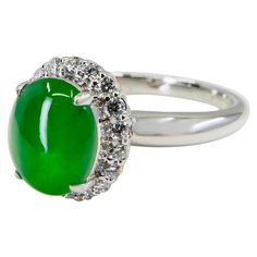 THIS JADE GLOWS! Here is a bright apple green oval high domed cabochon jade and diamond ring. This jade is one step away from being a true imperial jade! It is certified by 2 labs as natural jadeite jade with no treatment or enhancement. The ring is set in 18k white gold and diamonds. There are round shaped white diamonds surrounding the jade center stone. The white diamonds total 0.324 cts. The untreated / un-enhanced natural jade is very translucent. The color is bright apple green color. The Apple Green Color, Imperial Jade, Diamond Cocktail Ring, Green Oval, Diamond Cocktail Rings, Jade Ring, Natural Jade, Apple Green, Jewelry Business