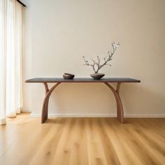 a table with two vases on it in front of a window