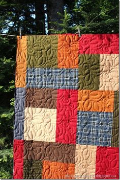 a quilt hanging on a clothes line in front of some trees