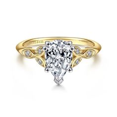 a yellow gold engagement ring with a pear shaped diamond in the center and side stones