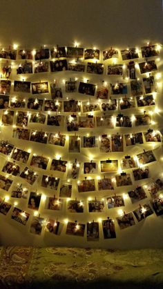 many pictures are hung on the wall with string lights and some candles in front of them