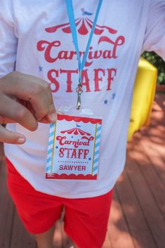 a person wearing a carnival staff shirt and red shorts with a blue lanyard around their neck