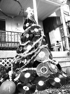 a black and white photo of a christmas tree made out of old record records in front of a house