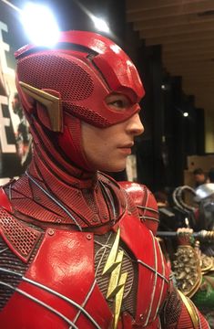 a close up of a person wearing a red flash suit and helmet in a room