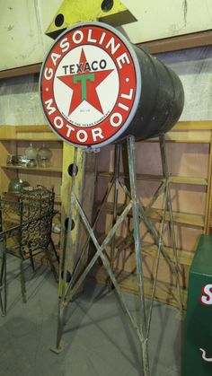 an old texaco oil sign sitting on top of a wooden stand in a garage