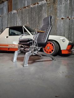 an orange and white car is parked next to a black leather chair in a garage