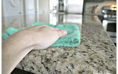 a person's hand holding a green towel on top of a granite countertop