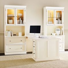 a desk with a computer on top of it next to a bookcase and cabinets