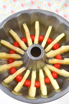 a metal pan filled with pineapples and cherries on top of a table