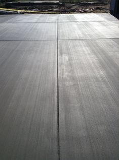 a skateboarder is doing a trick in the air on a concrete surface with trees and buildings in the background